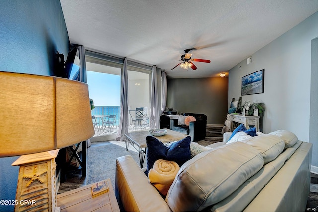 carpeted living room with ceiling fan, floor to ceiling windows, and a textured ceiling