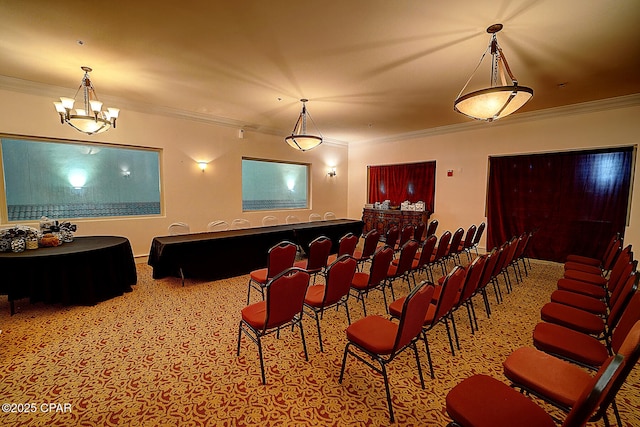 carpeted home theater room with ornamental molding and an inviting chandelier