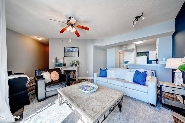 living room featuring light wood-type flooring, ceiling fan, and a textured ceiling