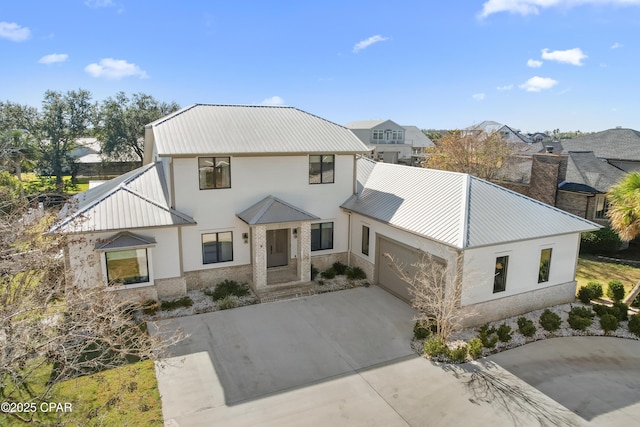 modern farmhouse featuring stucco siding, concrete driveway, a garage, and metal roof