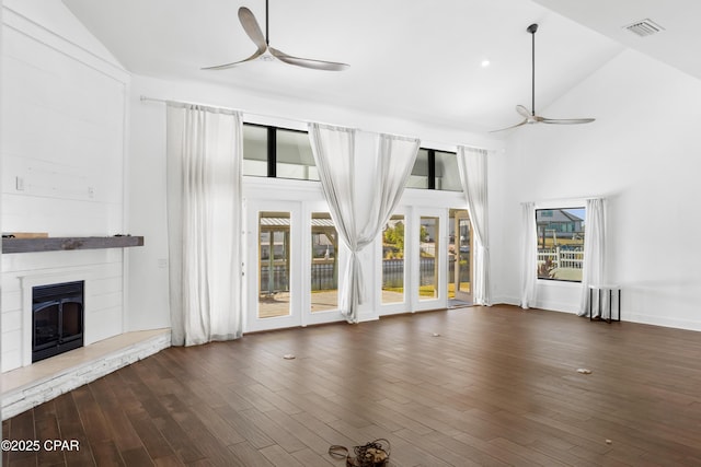 unfurnished living room with a glass covered fireplace, wood finished floors, visible vents, and ceiling fan