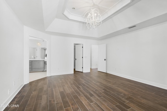 unfurnished room featuring dark wood finished floors, a notable chandelier, a raised ceiling, and visible vents