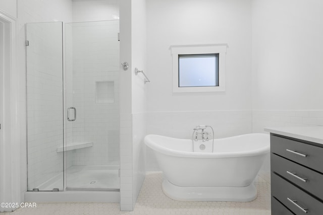 bathroom featuring a freestanding tub, a stall shower, tile walls, wainscoting, and vanity