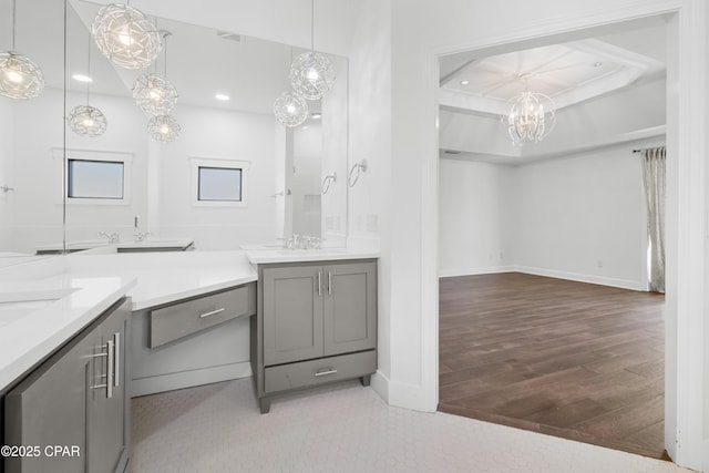 full bath with wood finished floors, two vanities, recessed lighting, a sink, and a raised ceiling