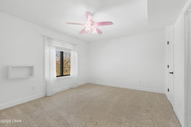 carpeted spare room with baseboards and a ceiling fan