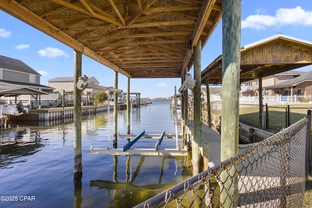 view of dock with fence, a water view, and boat lift