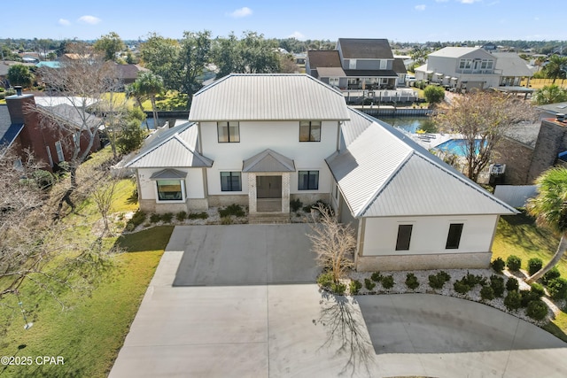 view of front of house featuring stucco siding, driveway, metal roof, and a standing seam roof