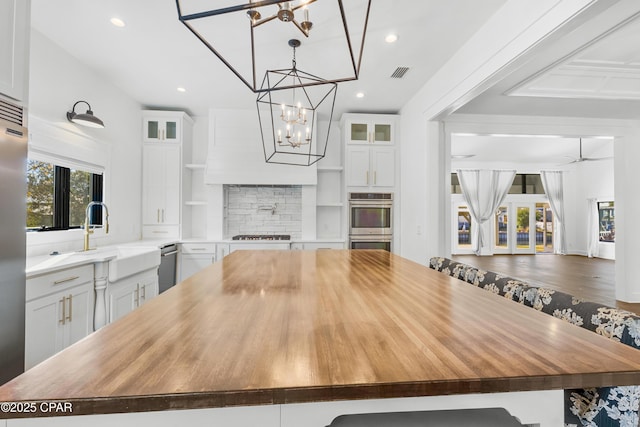 kitchen with visible vents, white cabinets, wooden counters, and a sink