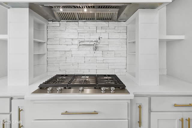 interior details with custom exhaust hood, light countertops, stainless steel gas stovetop, white cabinets, and tasteful backsplash