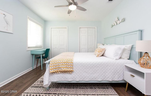 bedroom with ceiling fan, dark hardwood / wood-style floors, and two closets