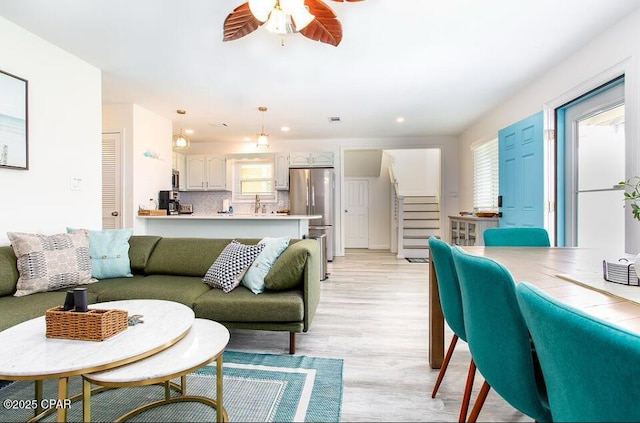 living room with light wood-type flooring, a wealth of natural light, and ceiling fan