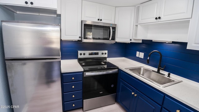 kitchen featuring blue cabinetry, stainless steel appliances, sink, and white cabinets