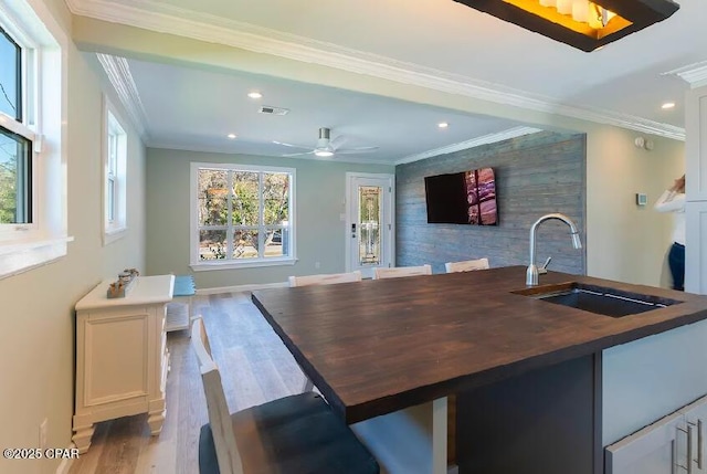 bar featuring light hardwood / wood-style floors, ceiling fan, ornamental molding, white cabinets, and sink