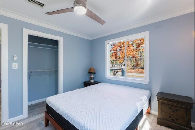 bedroom featuring light wood-type flooring, ceiling fan, a closet, and crown molding