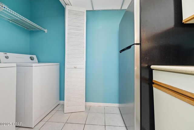 laundry area with washer and dryer and light tile patterned floors