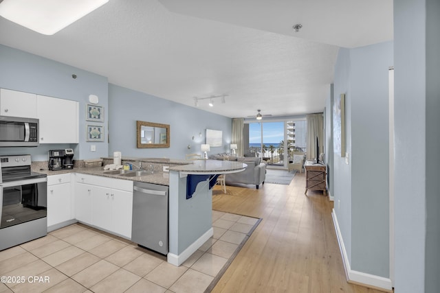 kitchen featuring a breakfast bar, sink, white cabinetry, appliances with stainless steel finishes, and kitchen peninsula