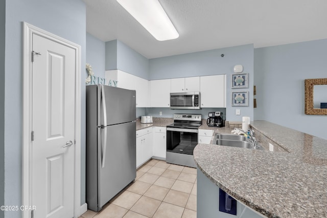 kitchen with appliances with stainless steel finishes, sink, light tile patterned floors, and white cabinets