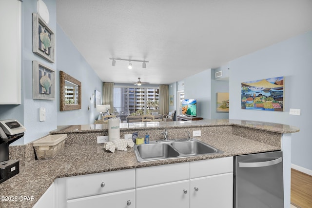 kitchen featuring sink, hardwood / wood-style flooring, white cabinetry, stainless steel dishwasher, and kitchen peninsula