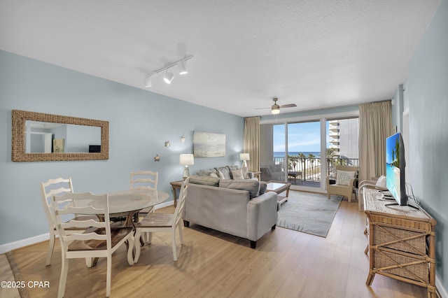 living room with ceiling fan, light hardwood / wood-style flooring, and a textured ceiling