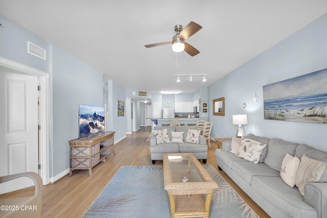 living room with ceiling fan and light hardwood / wood-style flooring