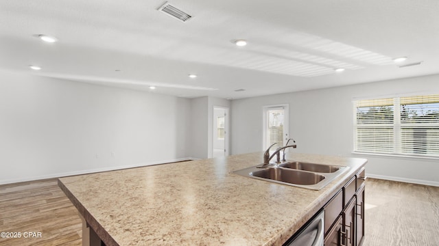 kitchen with sink, light hardwood / wood-style flooring, and an island with sink