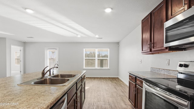 kitchen featuring stainless steel appliances, a wealth of natural light, sink, and light wood-type flooring