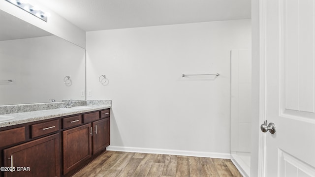 bathroom with walk in shower, wood-type flooring, and vanity