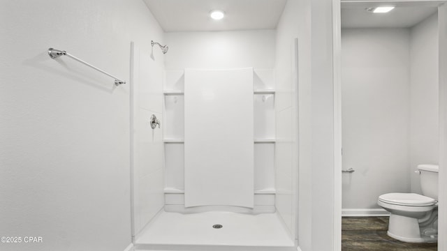 bathroom with hardwood / wood-style flooring, toilet, and walk in shower