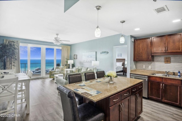 kitchen featuring pendant lighting, sink, a kitchen breakfast bar, stainless steel dishwasher, and a water view