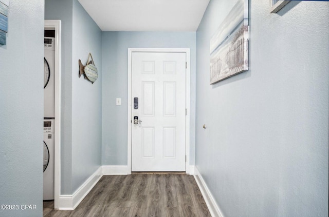 doorway to outside with stacked washer and dryer and wood-type flooring