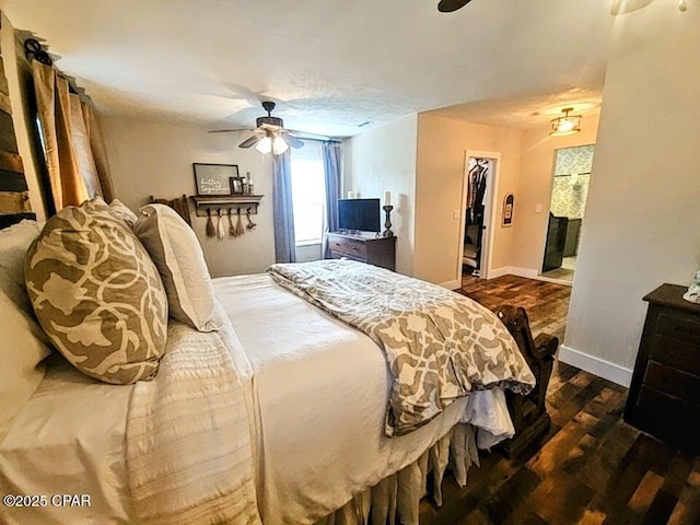 bedroom with ceiling fan, a spacious closet, a textured ceiling, dark hardwood / wood-style flooring, and a closet