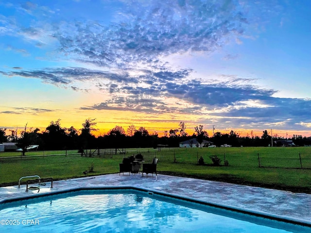 pool at dusk with a lawn and a patio area