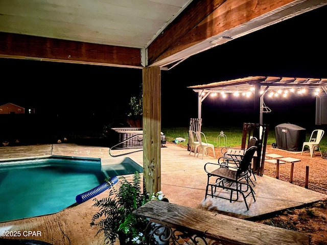 pool at night featuring a patio area