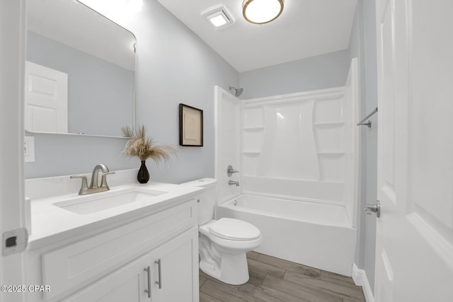 bathroom featuring toilet, tub / shower combination, wood finished floors, and vanity