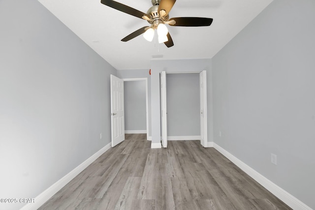 unfurnished bedroom featuring ceiling fan, a closet, wood finished floors, and baseboards