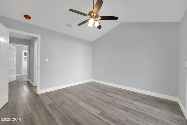 empty room with lofted ceiling, ceiling fan, baseboards, and wood finished floors