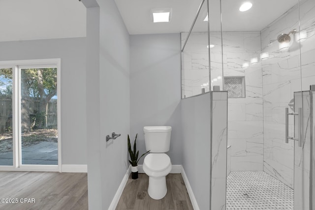 bathroom featuring toilet, a marble finish shower, baseboards, and wood finished floors