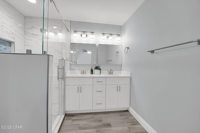 bathroom featuring double vanity, a marble finish shower, and a sink