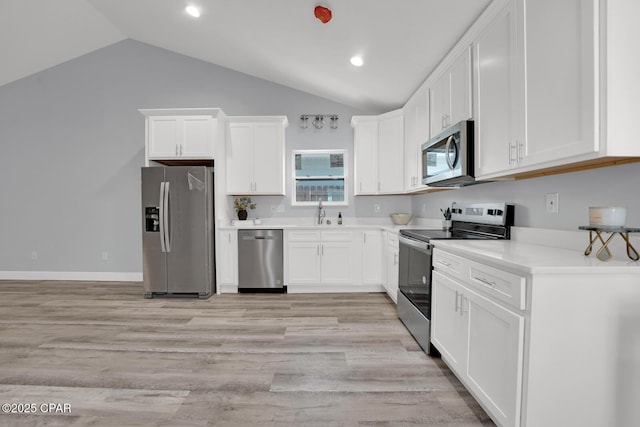 kitchen featuring lofted ceiling, stainless steel appliances, light wood-type flooring, and white cabinets