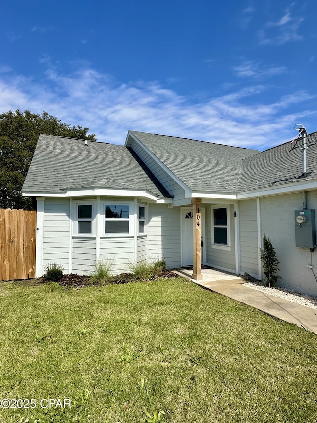 view of front of house featuring a front lawn, roof with shingles, and fence