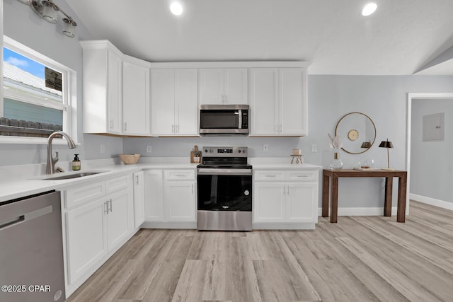 kitchen with stainless steel appliances, light countertops, a sink, and light wood finished floors