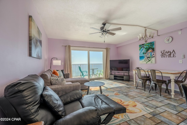 living room featuring ceiling fan with notable chandelier and a textured ceiling