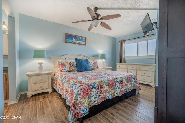 bedroom with a textured ceiling, ceiling fan, and light hardwood / wood-style floors