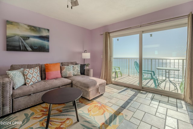 living room featuring ceiling fan and a water view