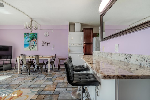 dining area featuring stacked washer and clothes dryer and an inviting chandelier