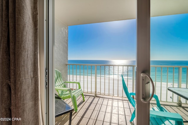 balcony with a water view and a view of the beach