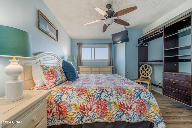 bedroom with a textured ceiling, ceiling fan, and dark hardwood / wood-style floors