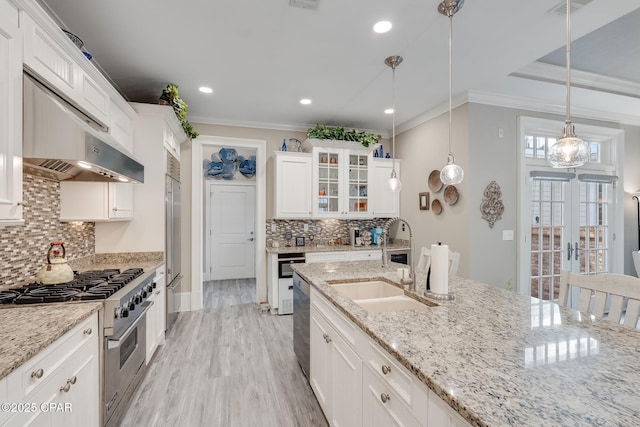 kitchen featuring light stone countertops, high quality appliances, sink, white cabinetry, and decorative light fixtures