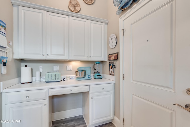 interior space featuring white cabinets, dark wood-type flooring, and built in desk