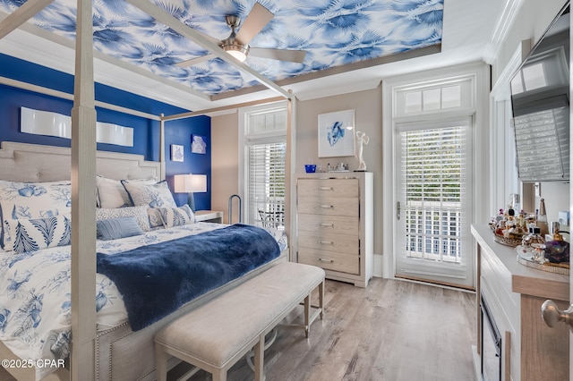 bedroom with ceiling fan, ornamental molding, a tray ceiling, light hardwood / wood-style flooring, and access to outside